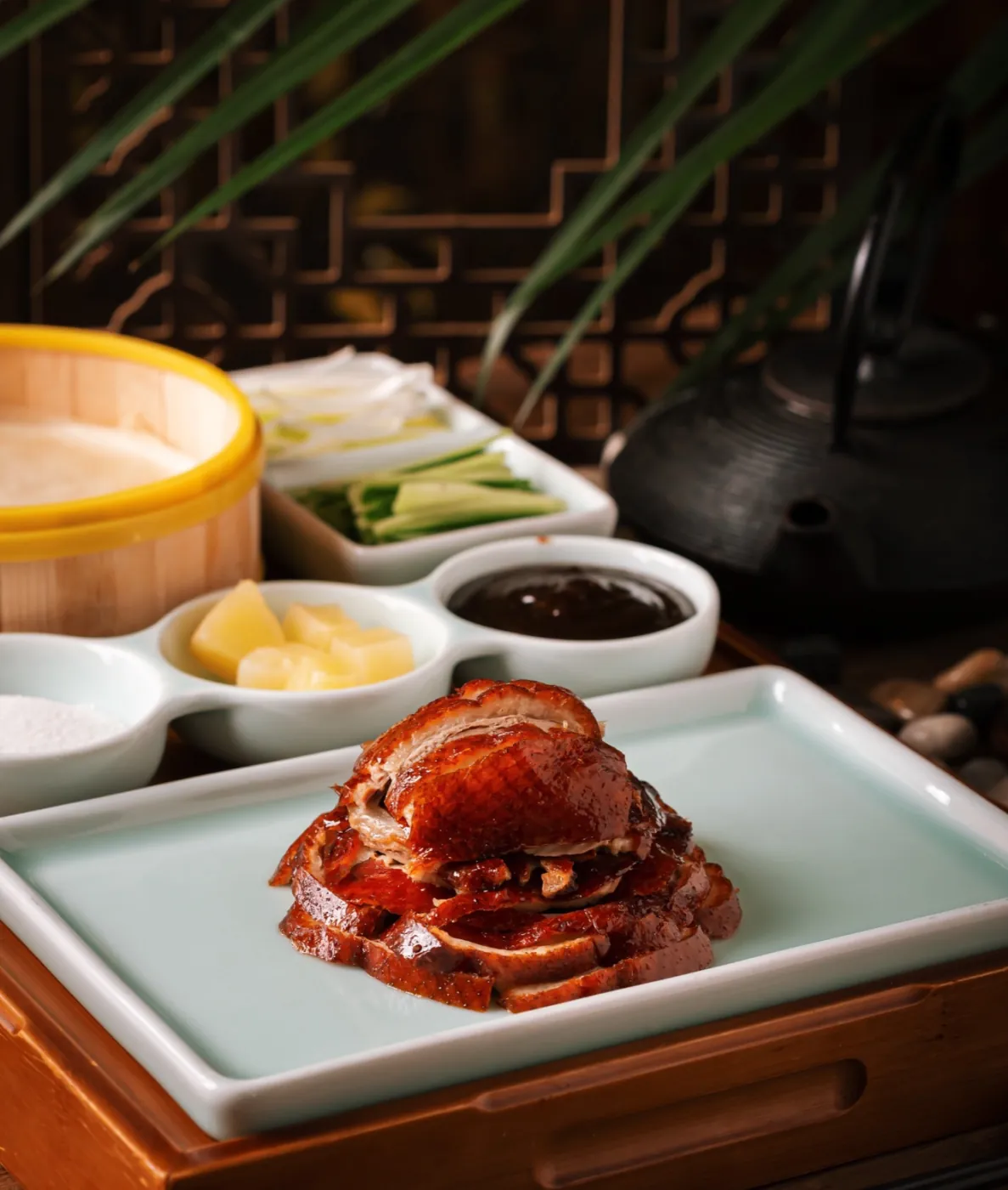 Sliced Peking duck arranged on a celadon plate with condiments and pancakes