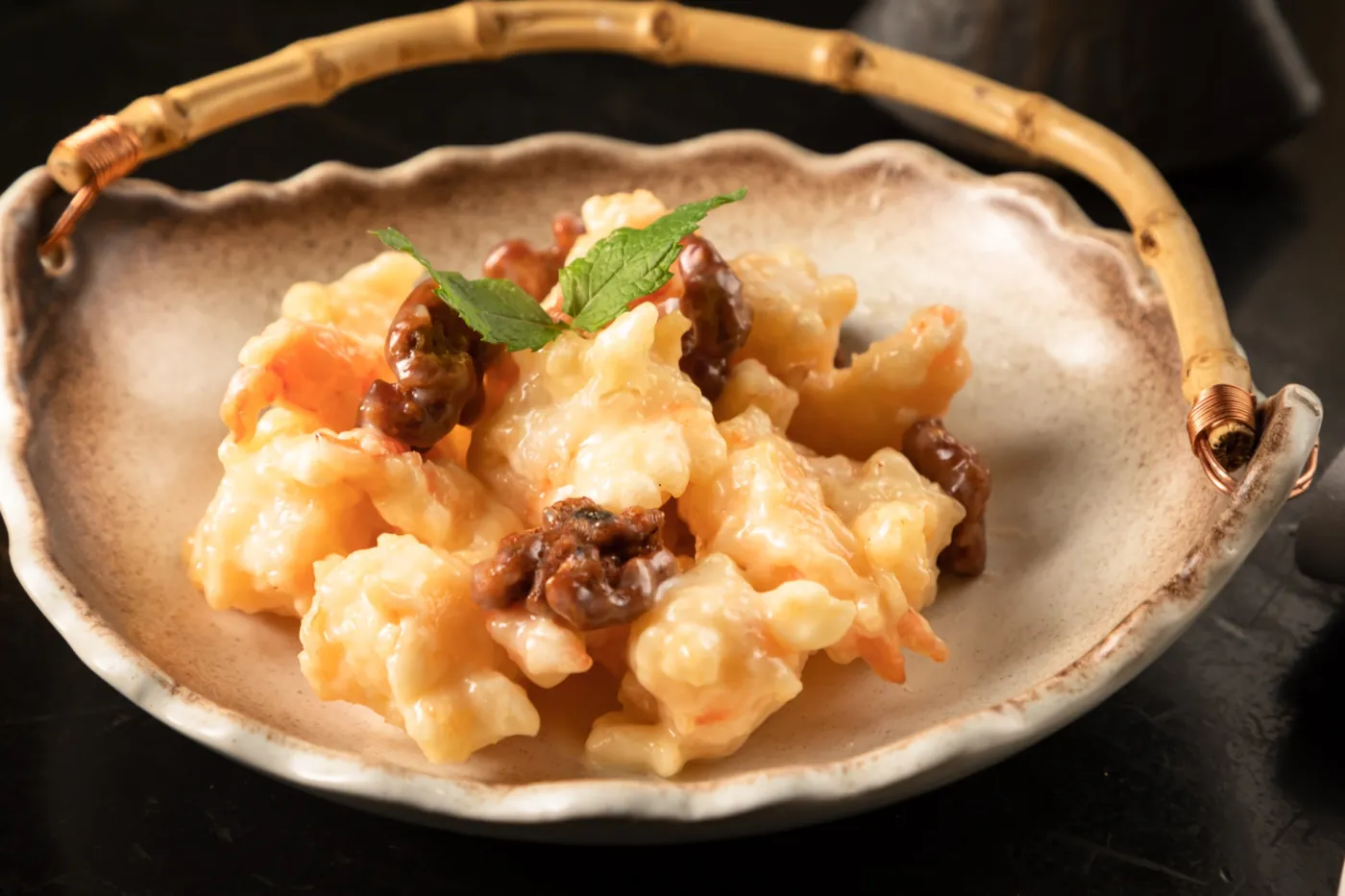 Honey walnut shrimp glazed in cream, crowned with candied walnuts and mint, in a ceramic bowl